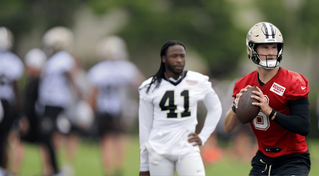 NFC South Camp Watch hero image featuring a quarterback in a red practice jersey during training camp.