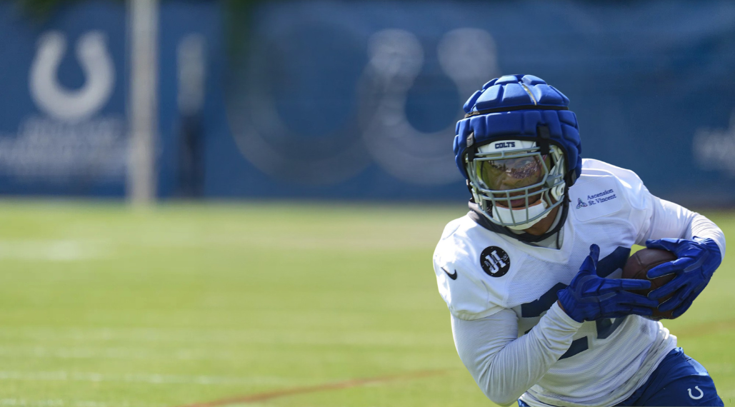 AFC South Camp Watch hero image featuring an Indianapolis Colts player carrying the football during training camp.
