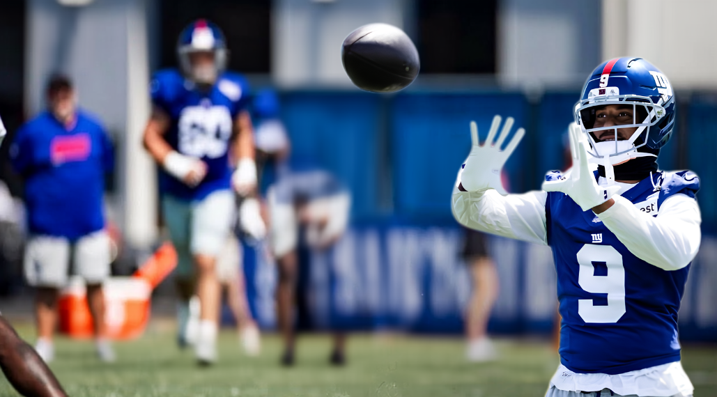 NFC East Camp Watch hero image featuring a New York Giants receiver tracking a pass during training camp.